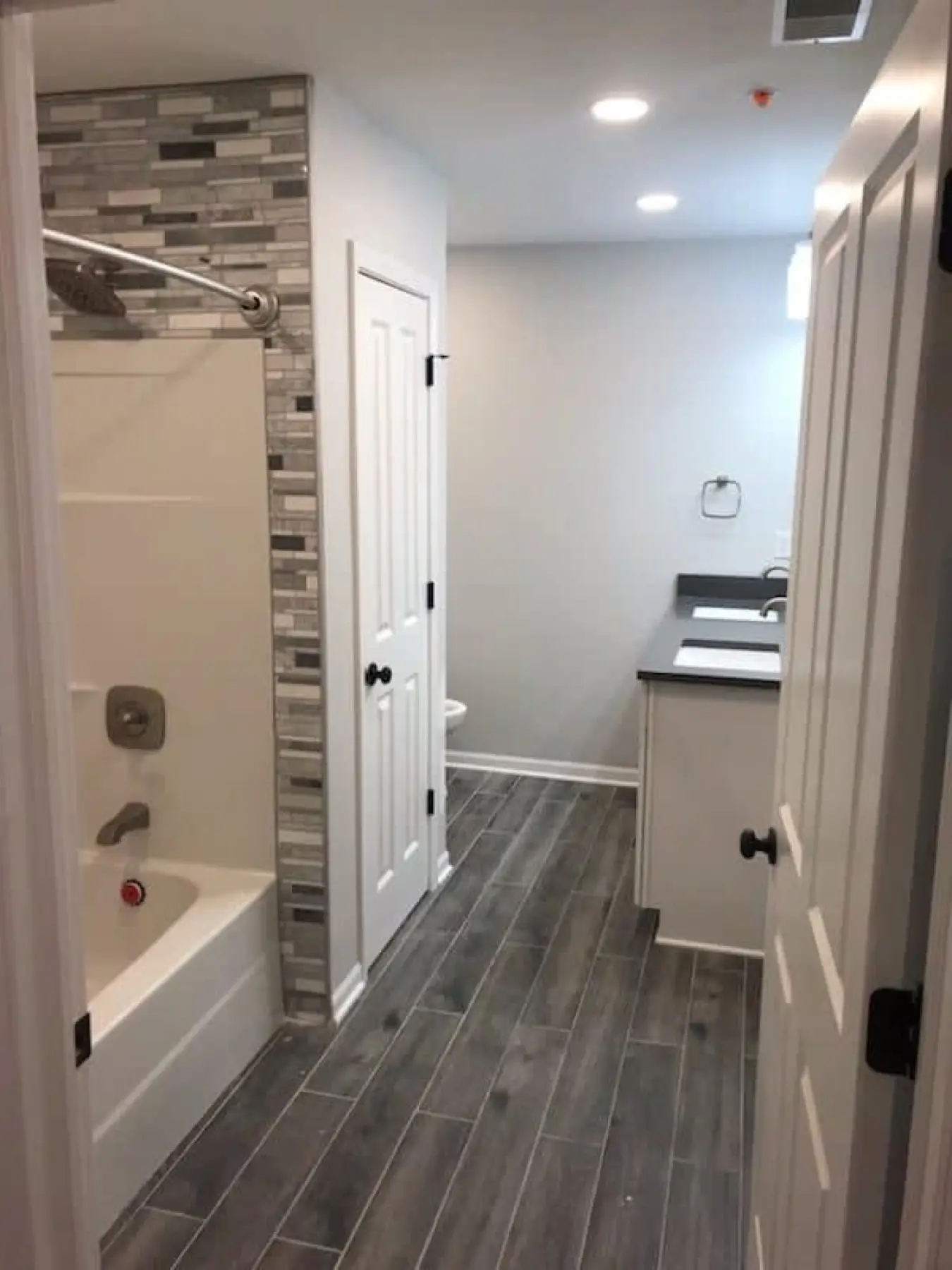 Finished tile shower with recessed lighting in a remodeled bathroom.