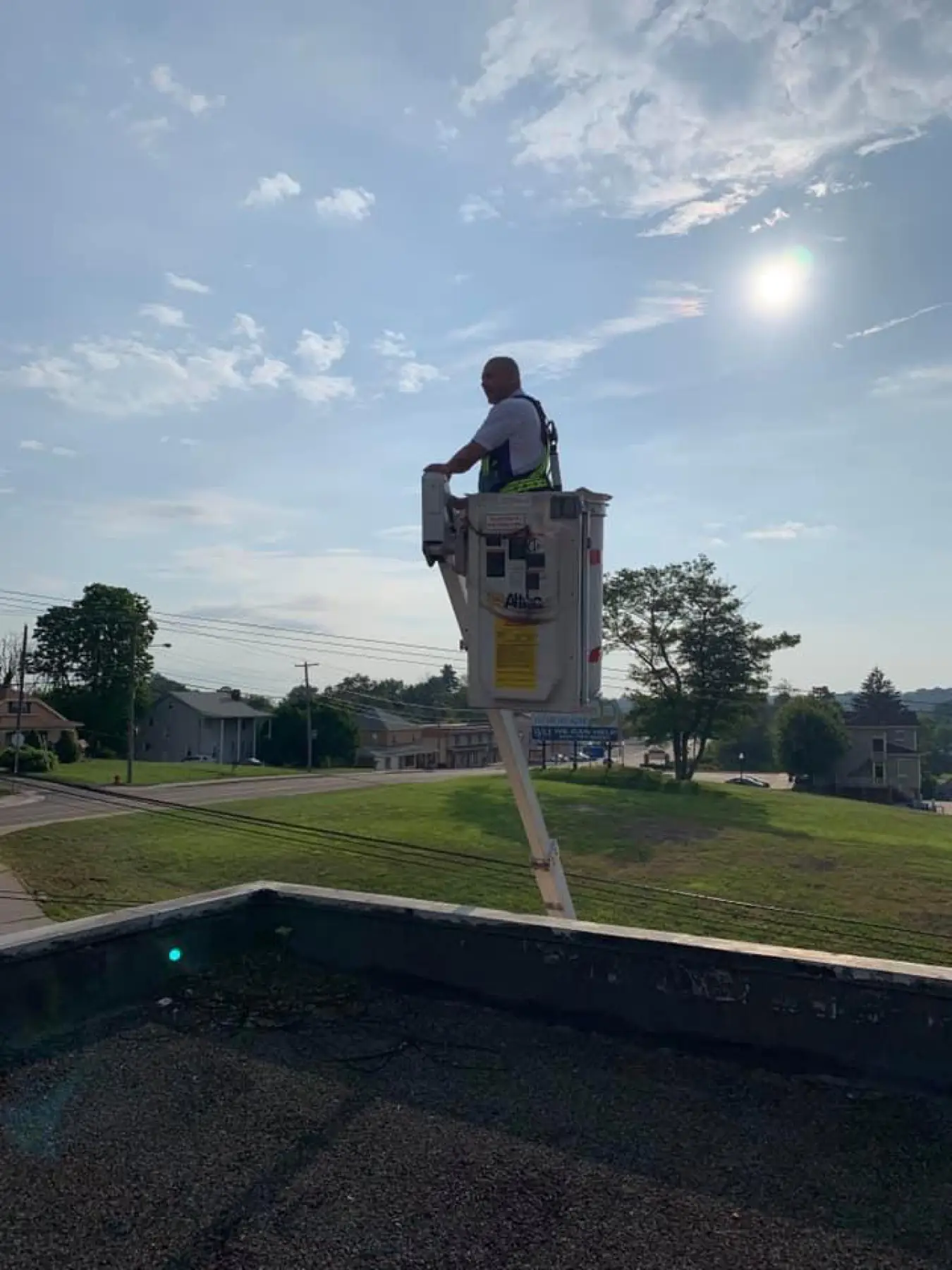 Bucket truck boom raised over a residential yard.