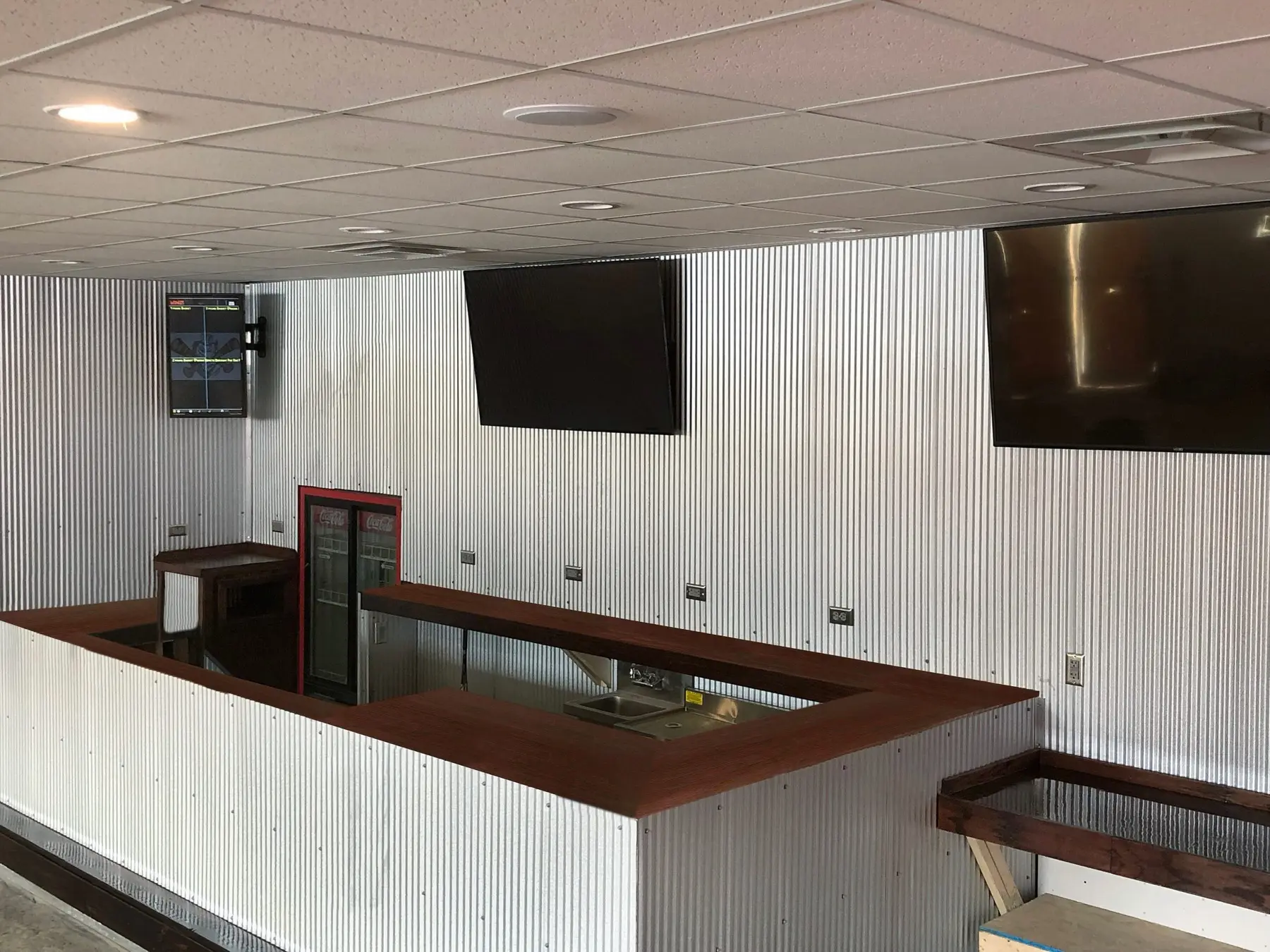Commercial lobby with a reception desk, recessed lighting and corrugated wall panels.