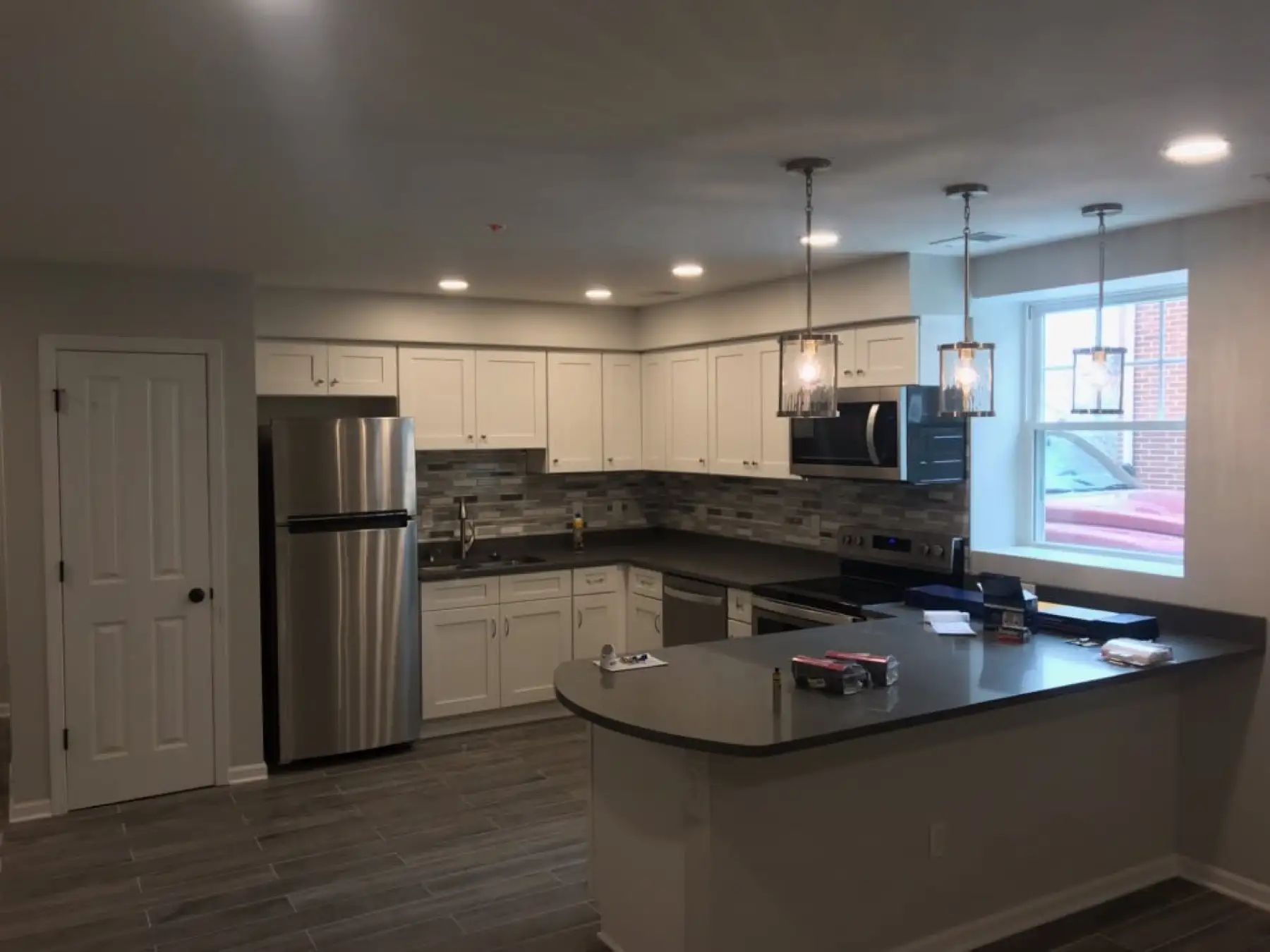 Finished kitchen with white cabinets, recessed lights and two pendants over the island.