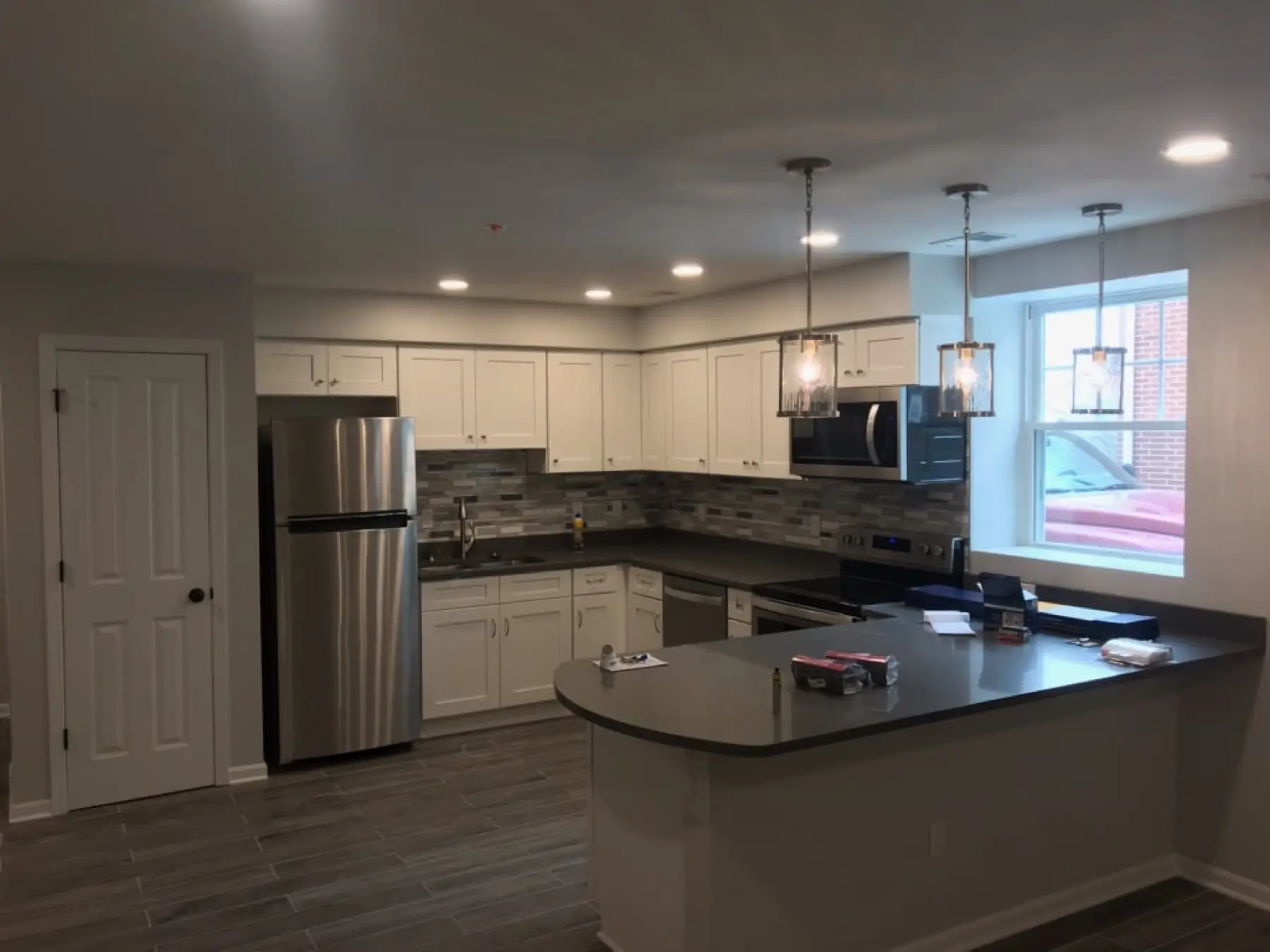 Finished kitchen with white cabinets, recessed lights and two pendants over the island.