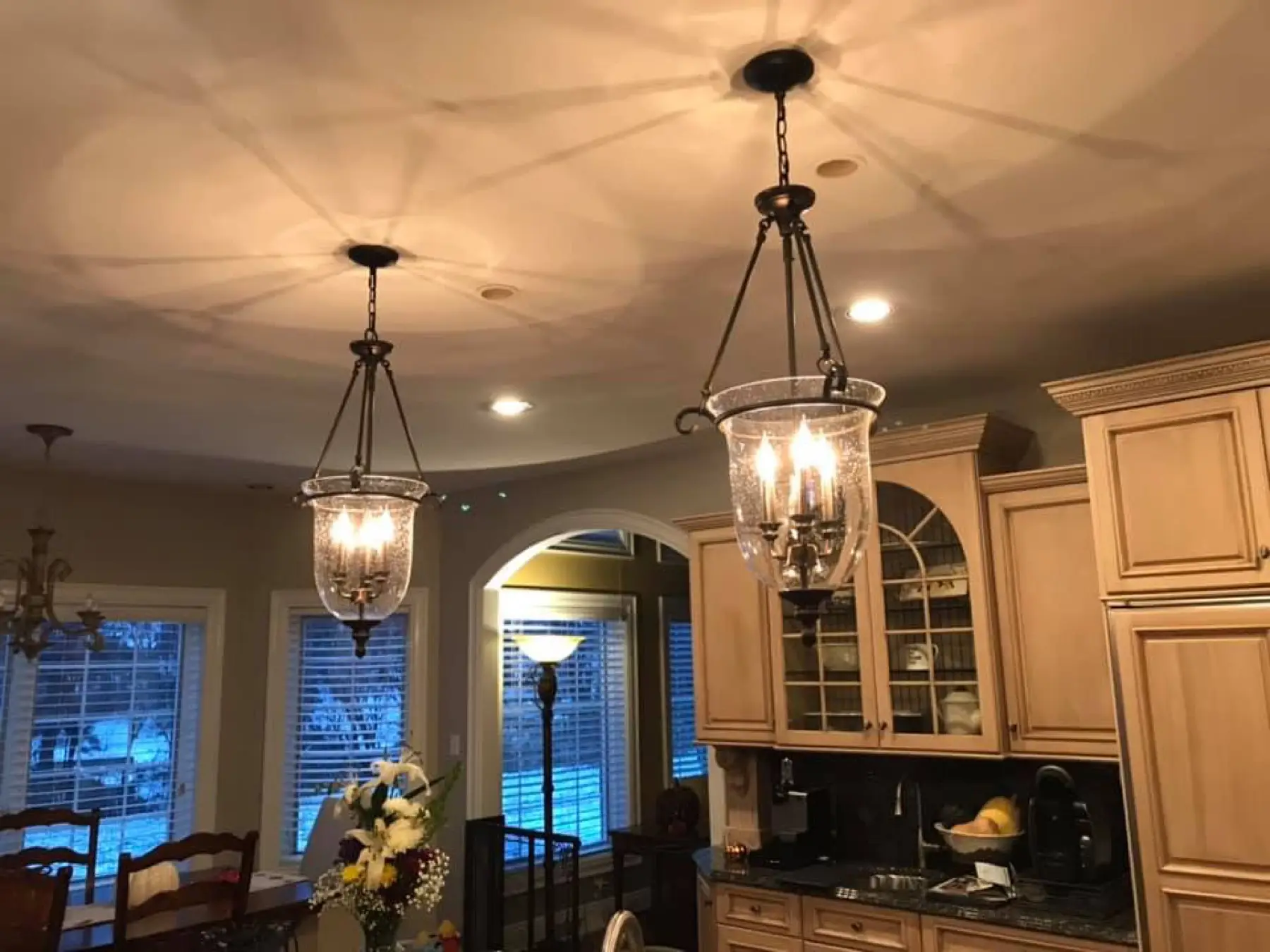 Kitchen with two lantern pendants over the island and a chandelier over the table.