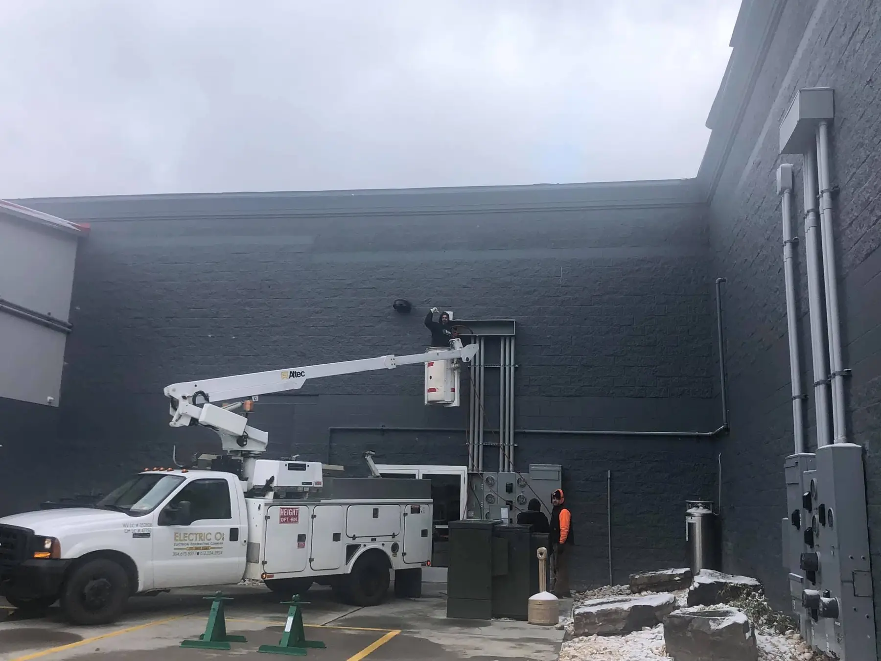 Bucket truck with boom raised against a commercial building.