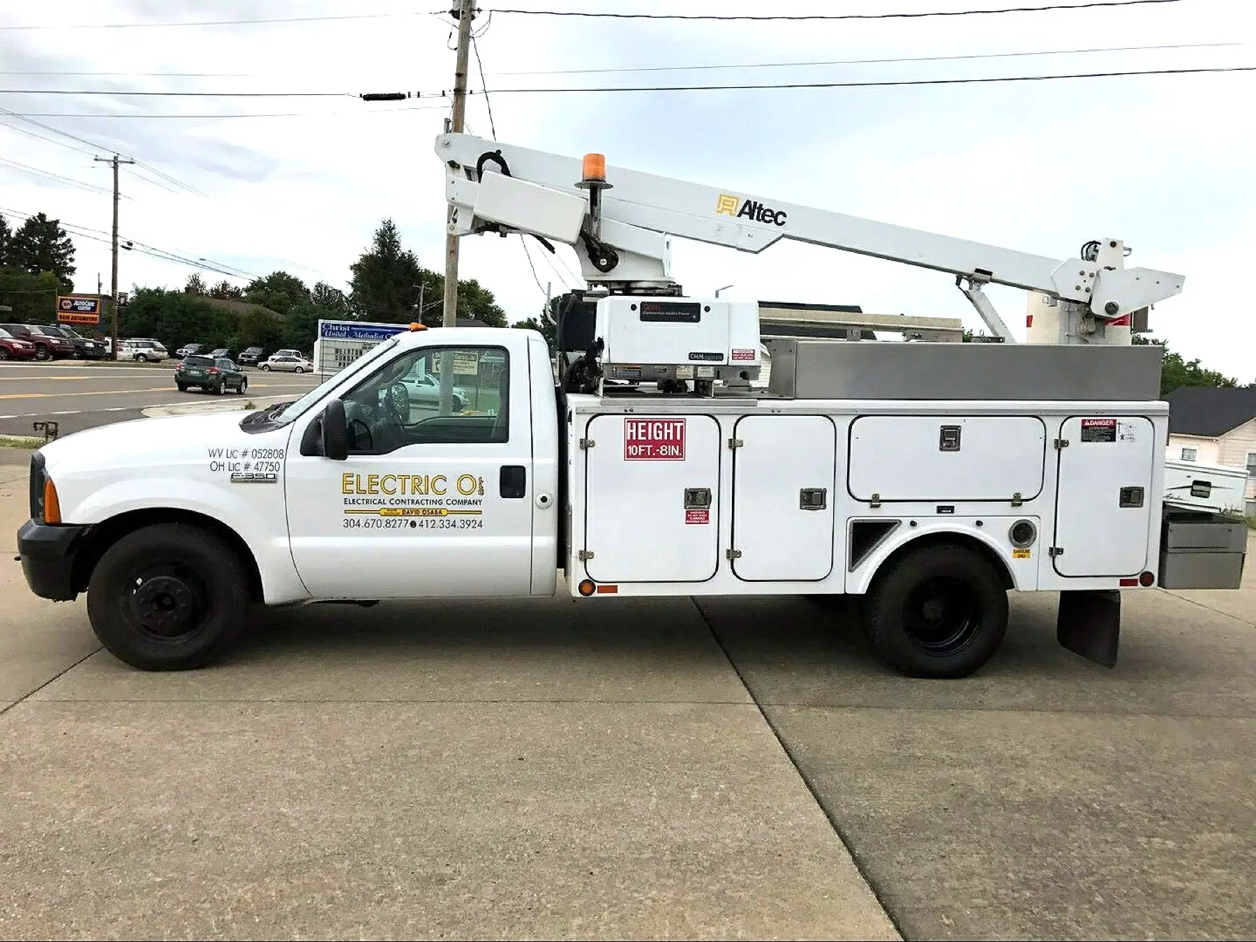 Electric O's white Altec bucket truck with yellow door lettering parked in a lot.